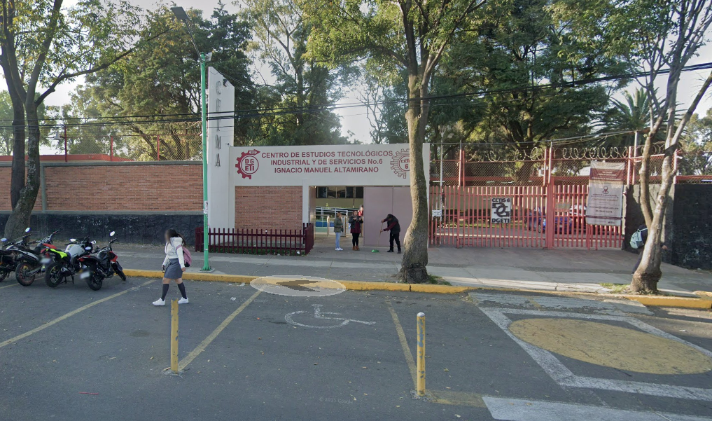 Fotografía en la que se muestra la entrada del plantel, conformada por un muro de tabique rojo, a su derecha se encuentra la puerta de acceso y arriba de ella, una placa blanca donde en letras rojas dice CENTRO DE ESTUDIOS TECNOLÓGICOS INDUSTRIAL Y DE SERVICIOS NÚMERO 6. IGNACIO MANUEL ALTAMIRANO